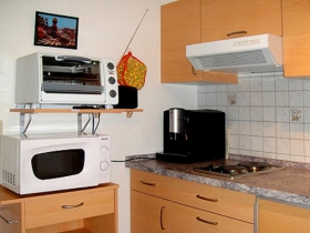 Einbauküche mit Mikrowelle und kleinem Backherd und Kühlschrank. Espresso-Vollautomat. Es ist auch noch eine kleine Kaffeemaschine vorhanden.